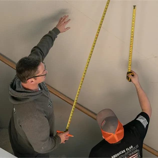 Two Tubro Construction team members measuring layout on an active remodel job site